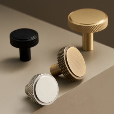 Solid brass knurled knob in unlacquered brass on plain background